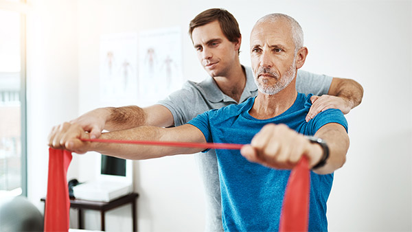 Ein Mann bekommt von einem Physiotherapeuten eine Übung gezeigt. Ein Mann bekommt von einem Physiotherapeuten eine Übung gezeigt.