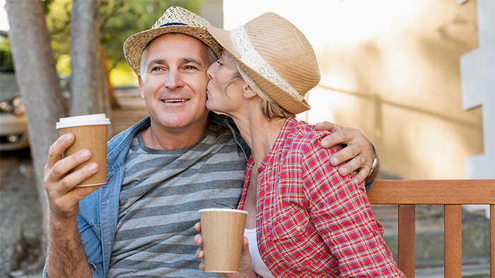 Mann und Frau sitzen verliebt mit einem Kaffeebecher auf einer Bank. Mann und Frau sitzen verliebt mit einem Kaffeebecher auf einer Bank.