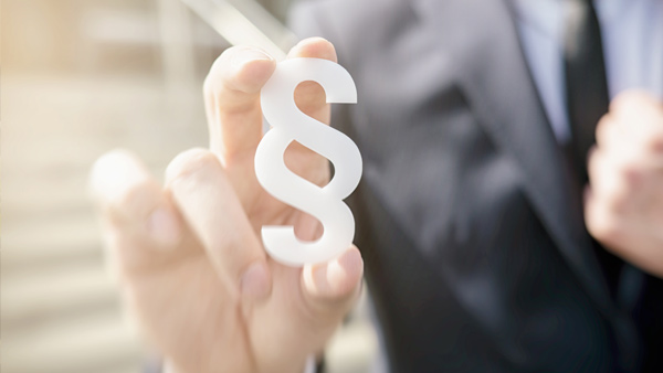 Eine Hand hält ein Paragraphenzeichen. Eine Hand hält ein Paragraphenzeichen.