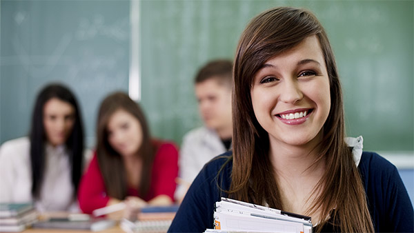 Eine Studentin mit Büchern. Im Hintergrund lernen drei Studenten. Eine Studentin mit Büchern. Im Hintergrund lernen drei Studenten.