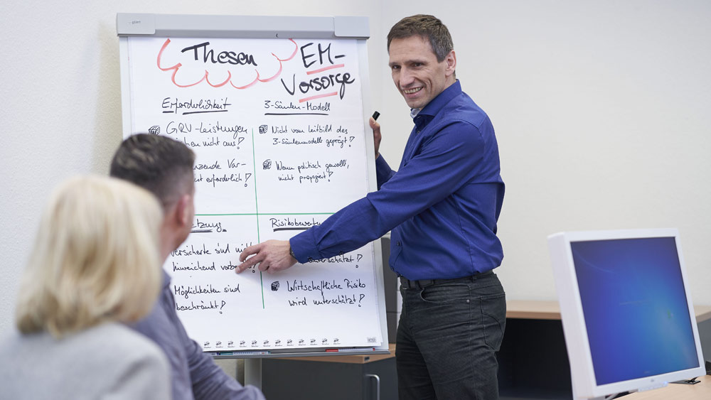 Marco Tempel, Referent in der Deutschen Rentenversicherung Knappschaft-Bahn-See, erläutert Sachverhalte an einem Flipchart.