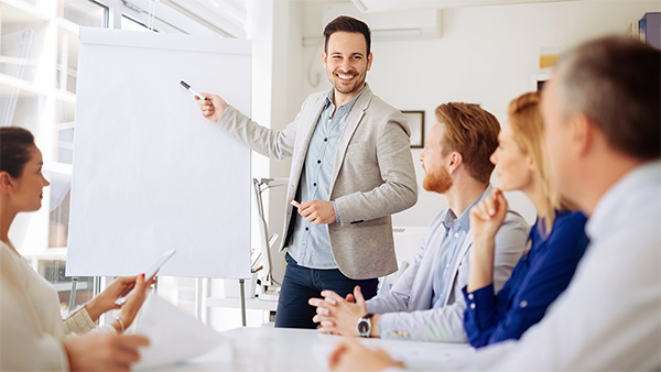 Ein Mann an einen Whiteboard und ein Team, das zu hört. Ein Mann an einen Whiteboard und ein Team, das zu hört.
