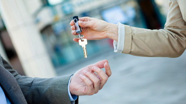 Eine Frau übergibt einem Mann einen Schlüssel. Nahaufnahme der Hände. Eine Frau übergibt einem Mann einen Schlüssel. Nahaufnahme der Hände.