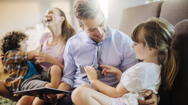 Ein Vater und eine Mutter beschäftigen sich mit ihren Kindern auf der Couch. Ein Vater und eine Mutter beschäftigen sich mit ihren Kindern auf der Couch.