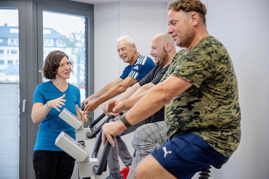 Eine Patientin auf einem Ergometer wird von einen Physiotherapeuten betreut. Eine Patientin auf einem Ergometer wird von einen Physiotherapeuten betreut.