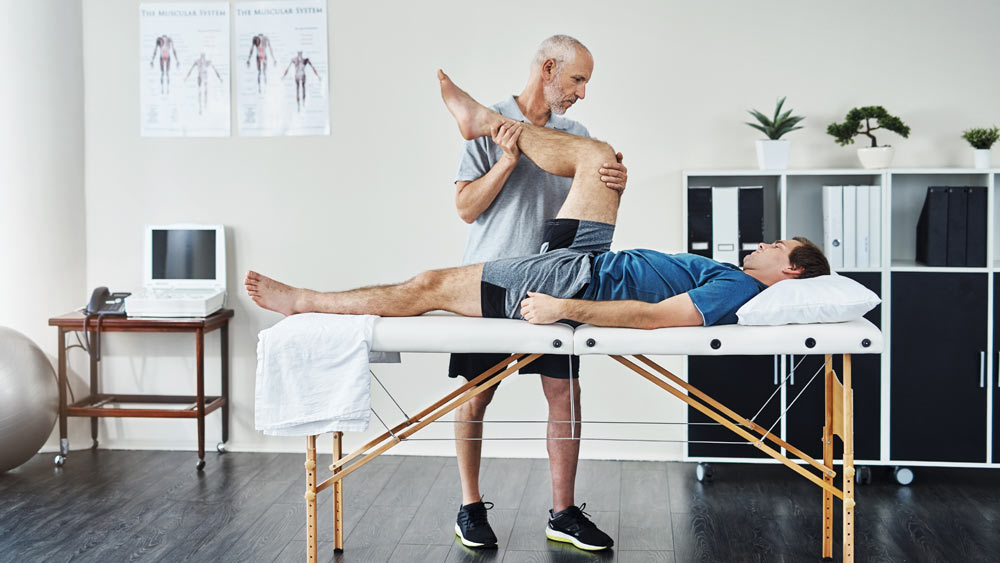 Ein Mann liegt auf einer Liege und wird von einem Physiotherapeuten behandelt. Ein Mann liegt auf einer Liege und wird von einem Physiotherapeuten behandelt.