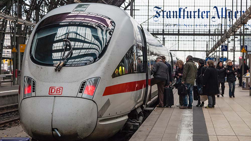 Ein ICE steht in einem Bahnhof. Eine Gruppe von Personen steigt ein.