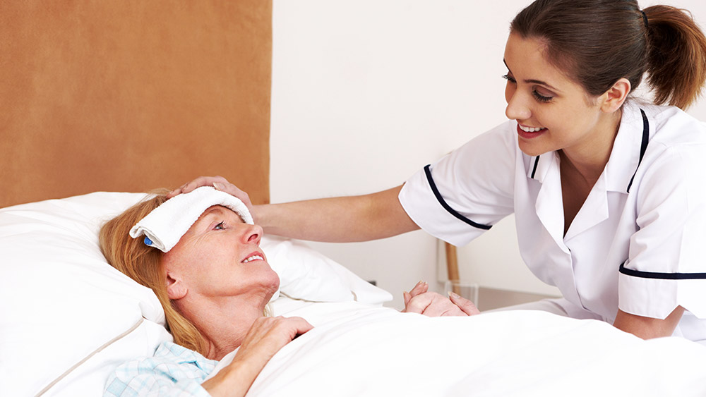 Eine ambulante Pflegerin kümmert sich um eine kranke, im Bett liegende Patientin. Eine ambulante Pflegerin kümmert sich um eine kranke, im Bett liegende Patientin.