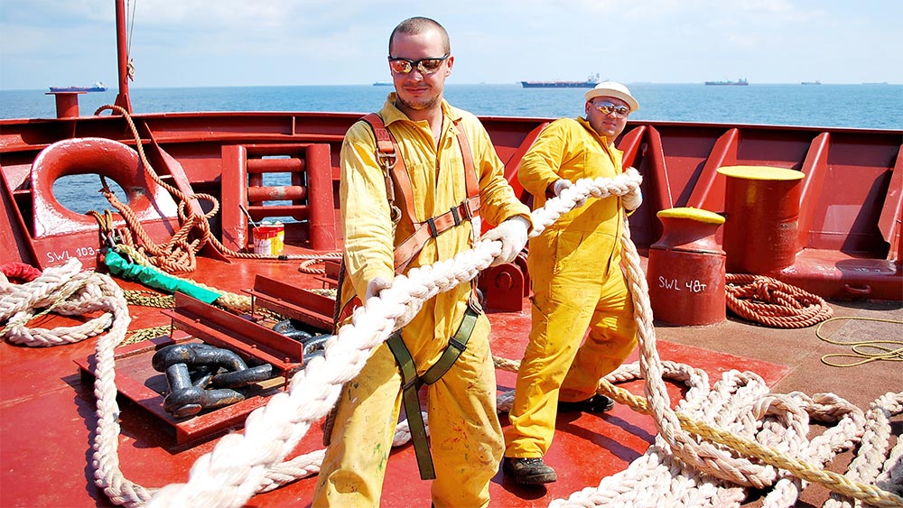 Two seamen with a rope in their hands on a ship